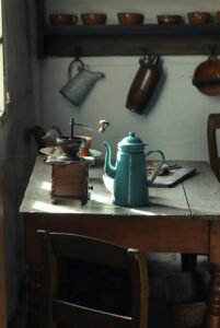 Cozy vintage kitchen interior with teapot and coffee grinder on wooden table.